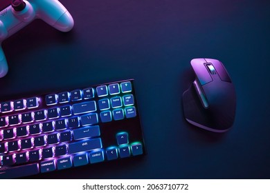 Top down view of color backlighted computer keyboard, mouse and game controller on desk. Professional computer game playing, esport business and online world concept. - Shutterstock ID 2063710772