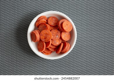 A top down view of a condiment cup of mini pepperonis.