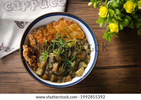 Top down view of a curry with chicken katsu on a wooden table