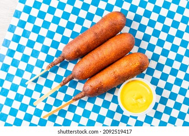 Top Down View Of Deep Fried Corn Dog Sausages On A Stick With Mustard At A Roadside Diner Or Fall Fair