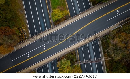 A top down view directly above a highway during the day with green trees and grass along the road. Taken by a drone camera showing the beautiful Long Island, NY landscape.