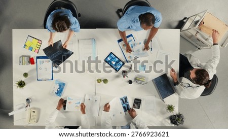 Top down view of doctors participating in a healthcare team meeting to review patient care. The discussion focuses on treatment planning and advancement in modern medicine.