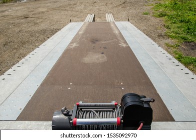 Top Down View Of Empty Flatbed Tow Truck Trailer Hauling Platform With Hydraulic Equipment Manipulator. Roadside Heavy Haul Car Carrier For Long-distance Towing Service Concept