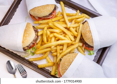 A Top Down View Of A Family Burger Combo, Featuring Four Wrapped Hamburgers And French Fries On A Tray, In A Restaurant Or Kitchen Setting.