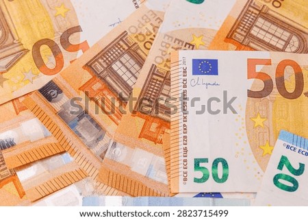 Top down view of fifty and twenty euro banknotes scattered over the entire surface, full frame background texture showing wealth and cash reserves