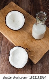 Top Down View Of Freshly Opened Coconut And A Bottle Of Coconut Juice Water Milk On A Wooden Work Top. Space Available For Copy Text