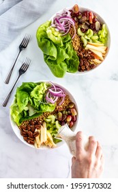 Top Down View Of A Hand Pouring Salad Dressing Onto A Waldorf Salad Bowl.