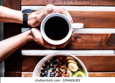 Top Down View Of Hands Taking A Cup Of Coffee With Muesli Yogurt Bowl