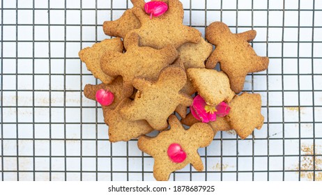 Top Down View Of Holiday Brown Delicious Star Cookies, Christmas Trees Cookies, Over A Black Grid With Flowers And Decorations