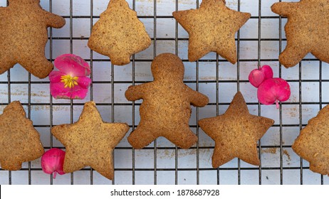 Top Down View Of Holiday Brown Delicious Star Cookies, Christmas Trees Cookies, Over A Black Grid With Flowers And Decorations