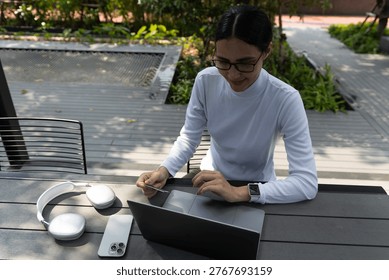 Top down view including the face of a Latina woman holding a credit card for ecommerce shopping.