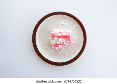 Top Down View Of Japanese Sweet Rice Cake Mochi On A Plate. Two Slices Of Chi Chi Dango, Pink And White Mochi With Powdered Mochiko Against A White Background.