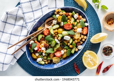 Top down view of a large mediterranean salad surrounded by lemon wedges and spices, ready for serving - Shutterstock ID 1968043771