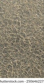 Top down view of light refracting through water on clean sand. 