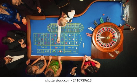 Top Down View: Luxurious Casino Male and Female Guests Putting Betting Chips on a Gambling Table, Trying to Predict the Outcome of a Roulette Game - Powered by Shutterstock