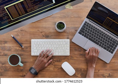 Top Down View At Male Hands Typing On Keyboard At Contemporary Workplace With Computers And Coffee Cup On Textured Wooden Table, Copy Space