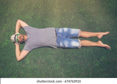 Top Down View Of Man In Hat And Sunglasses Lying In The Grass