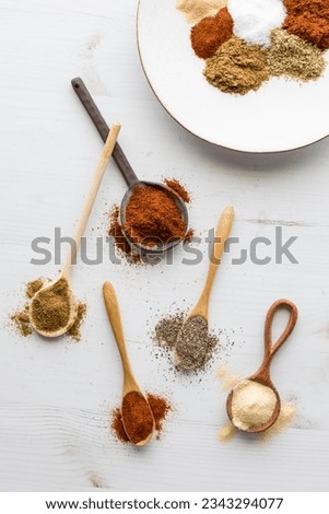 Top down view of messy spoons of spices used to make a taco seasoning blend.