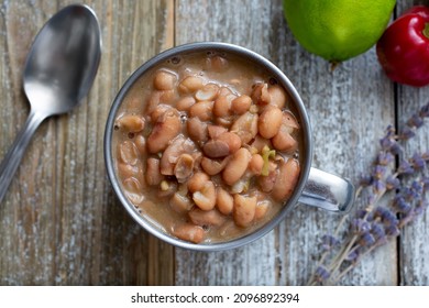 A Top Down View Of A Metal Cup Of Cooked Pinto Beans.