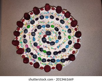 Top Down View On A Birthday Cake Decorated With Berries And Candy Forming A Spiral On Cream.