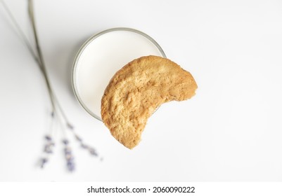 Top Down View On Bitten Off Cookie On Glass Of Milk With Lavender Sprigs On Background. Selective Focus