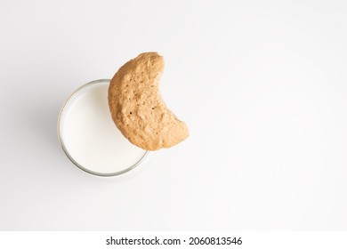 Top Down View On Bitten Off Cookie On Glass Of Milk On White Background. Selective Focus