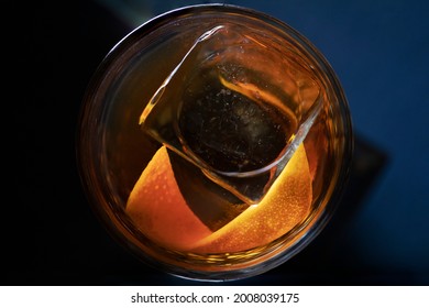 Top Down View On Cocktail Glass With Large Ice Cube And Orange Peel