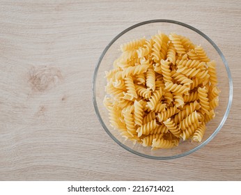 Top Down View On Fusilli Pasta In A Glass Bowl On A Wooden Table In Natural Light