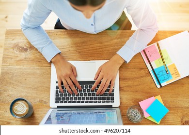 Top Down View On Pair Of Female Hands Of Woman Typing On Laptop Computer With Coffee And Office Supplies Next To It