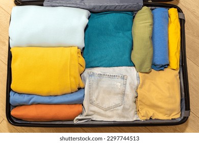 Top down view of an open suitcase filled with travel clothes. The concept of summer holidays, travel, airplane flights.