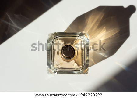 Top down view of a perfume bottle with reflections and contrasting shadows.