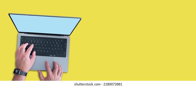 Top Down View Of Person Using Modern Laptop Computer With Copy Space On Screen Against Wide Yellow Background