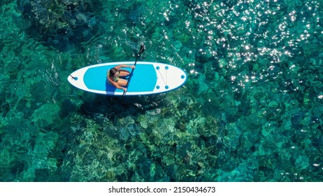 Top down view picture of a woman paddling on her knees on the sup board.