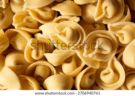 A top down view of a pile of raw gluten-free tortelloni, as a background.