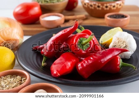 A top down view of a pile of red Fresno chiles, among other salsa ingredients.