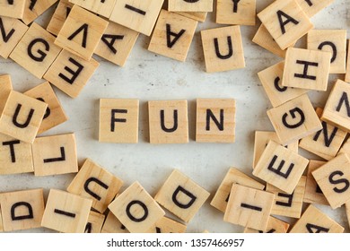 Top down view, pile of square wooden blocks with word FUN on white board. 