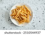 A top down view of a plate of crinkle cut french fries.