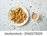 A top down view of a plate of loaded tots, with a condiment cup of thousand island dressing.