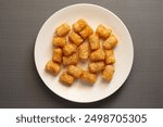 A top down view of a plate of tater tots.