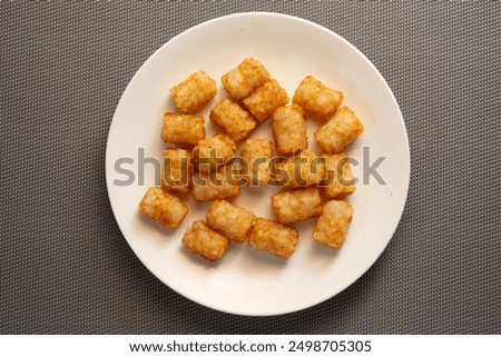 A top down view of a plate of tater tots.