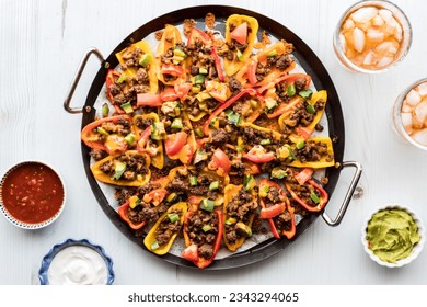 Top down view of a platter of mini bell pepper nachos served with dips.