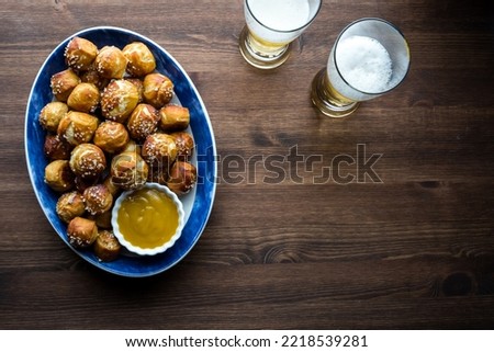 Top down view of a platter of pretzel bites served with mustard sauce and beer.