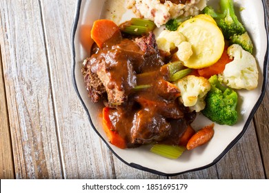 A Top Down View Of A Pot Roast Plate, Featuring Steamed Veggies And Mashed Potatoes.