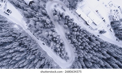 Top down view of road going through the forest in winter snow landscape. Drone elevated in the mountain countryside covered with snow in Jasna, Low Tatras, Slovakia.