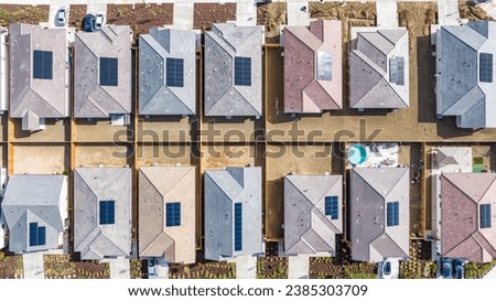 Top down view of a row of residential homes with solar panels on the roof 