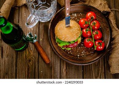 Top down view of rustic serving classic beef burger with glass of beer, on wooden table. gastro pub. Homemade cooking 