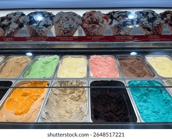 The top down view of several large, commercial grade tubs of ice cream in a variety of flavors. 