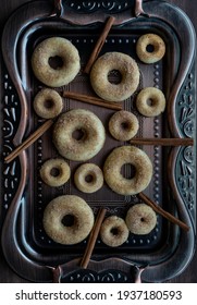 Top down view of several two different size donuts on a decorative vintage pan.
