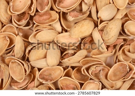 A top down view shows a dense pile of empty open pistachio nutshells creating a textured natural background pattern.