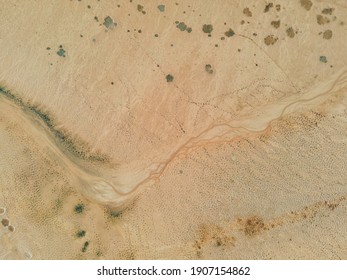 Top down view: small stream of water at the bottom of a dry lake. The unearthly landscape of the bottom of the lake.